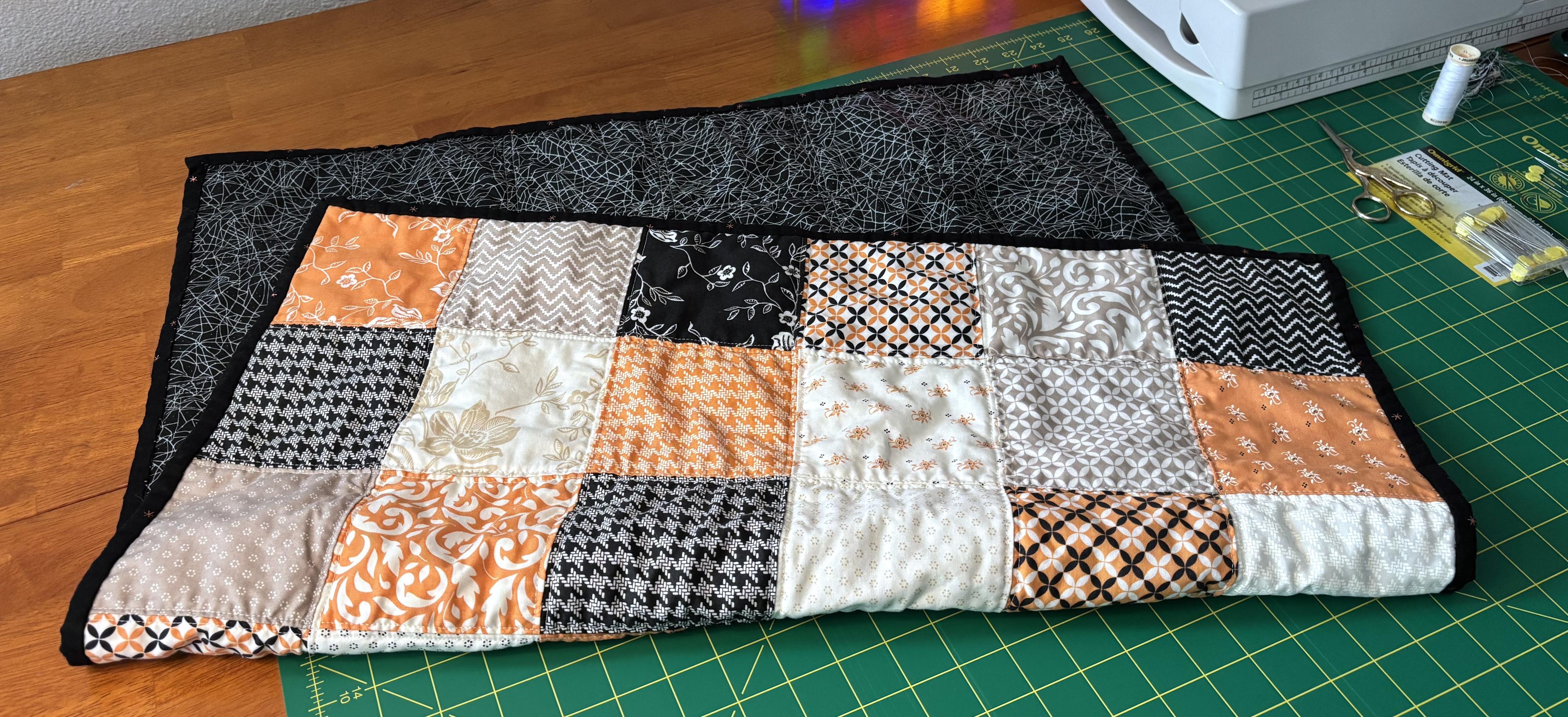 Finished quilt folded over once, resulting in half the quilt top and half the backing being visible.