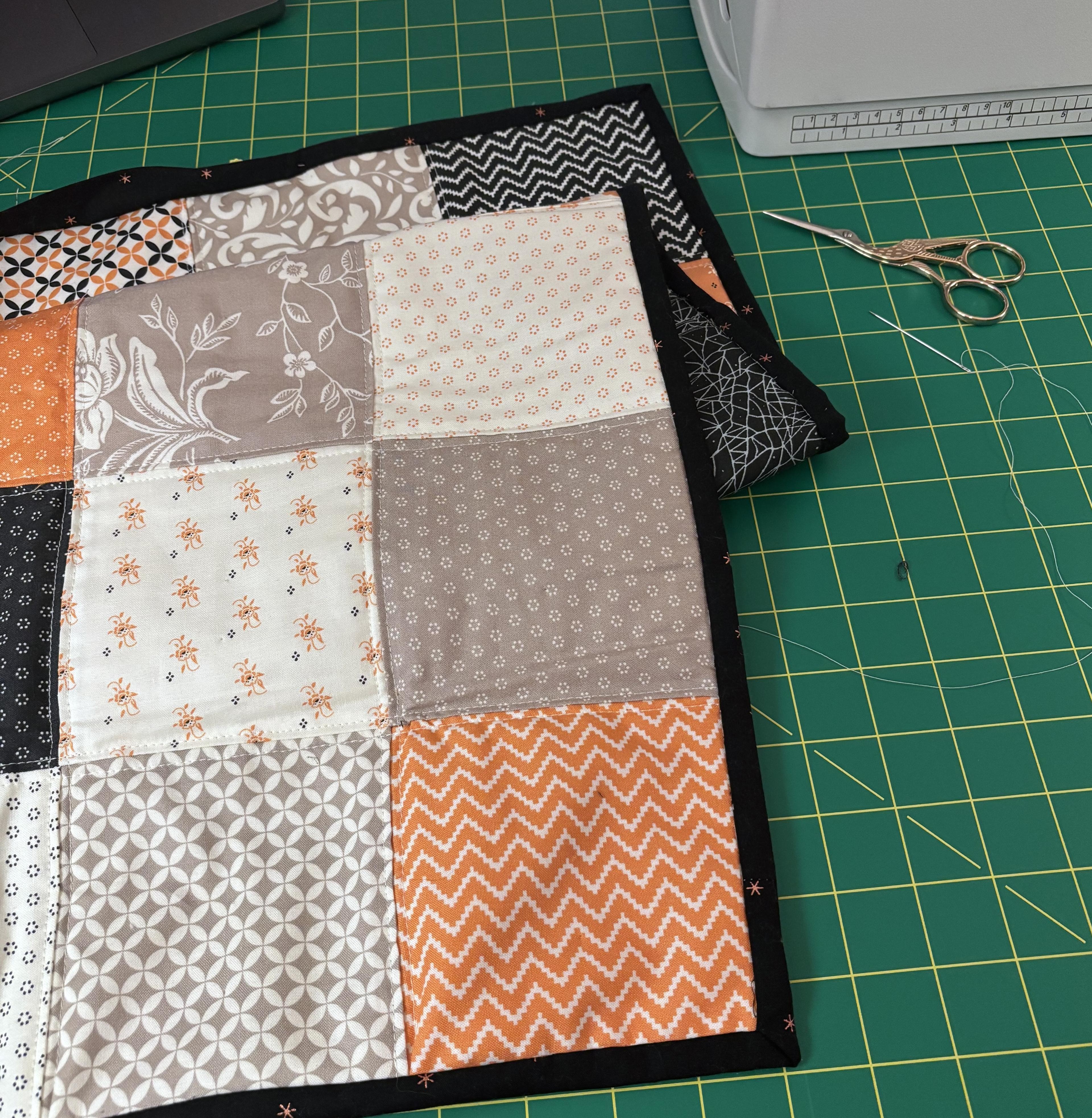 The in-progress quilt folded over, in progress hand-stitching the binding to the back.
