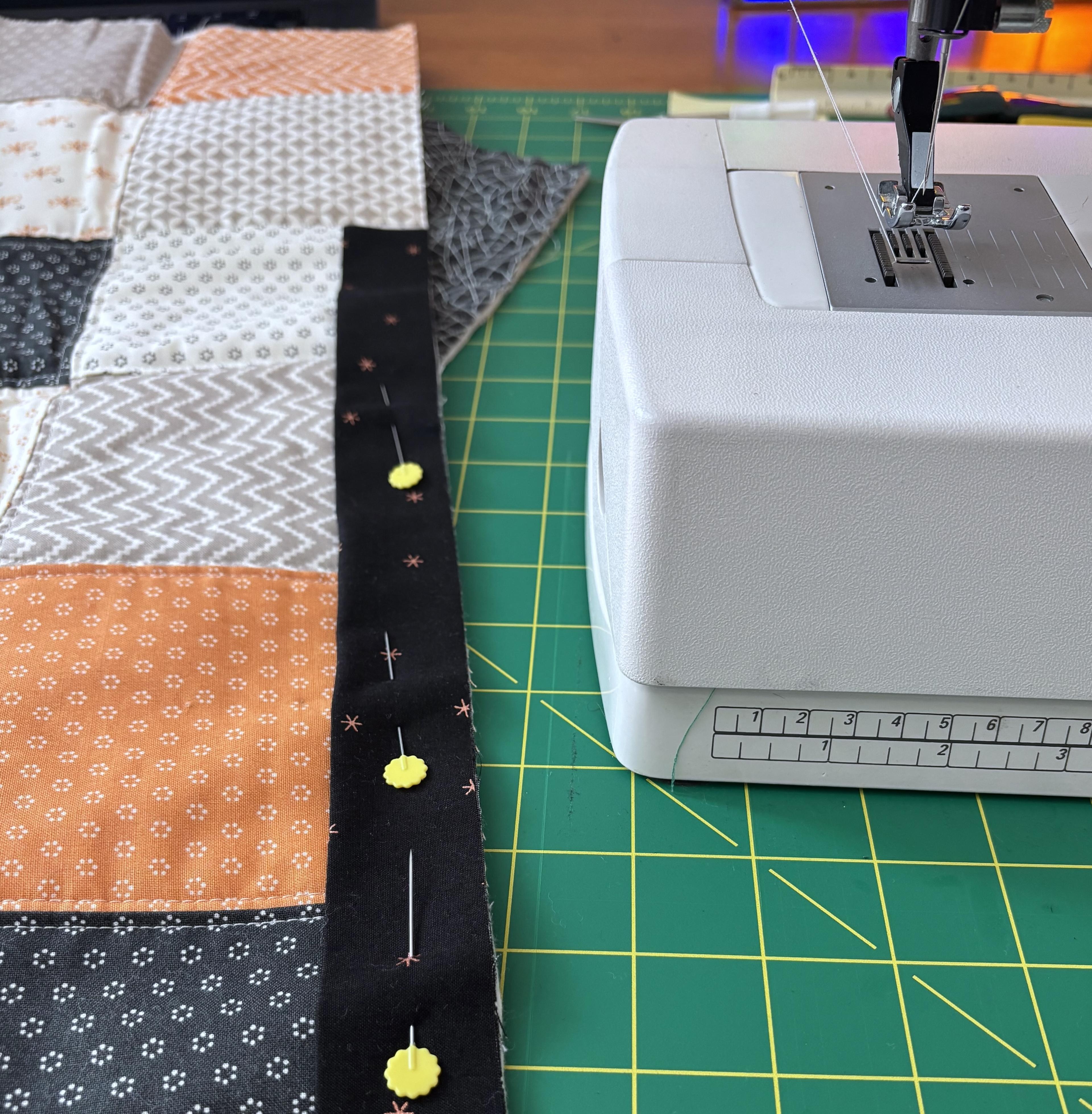 A close up of the binding being pinned to the edge of the quilt.
