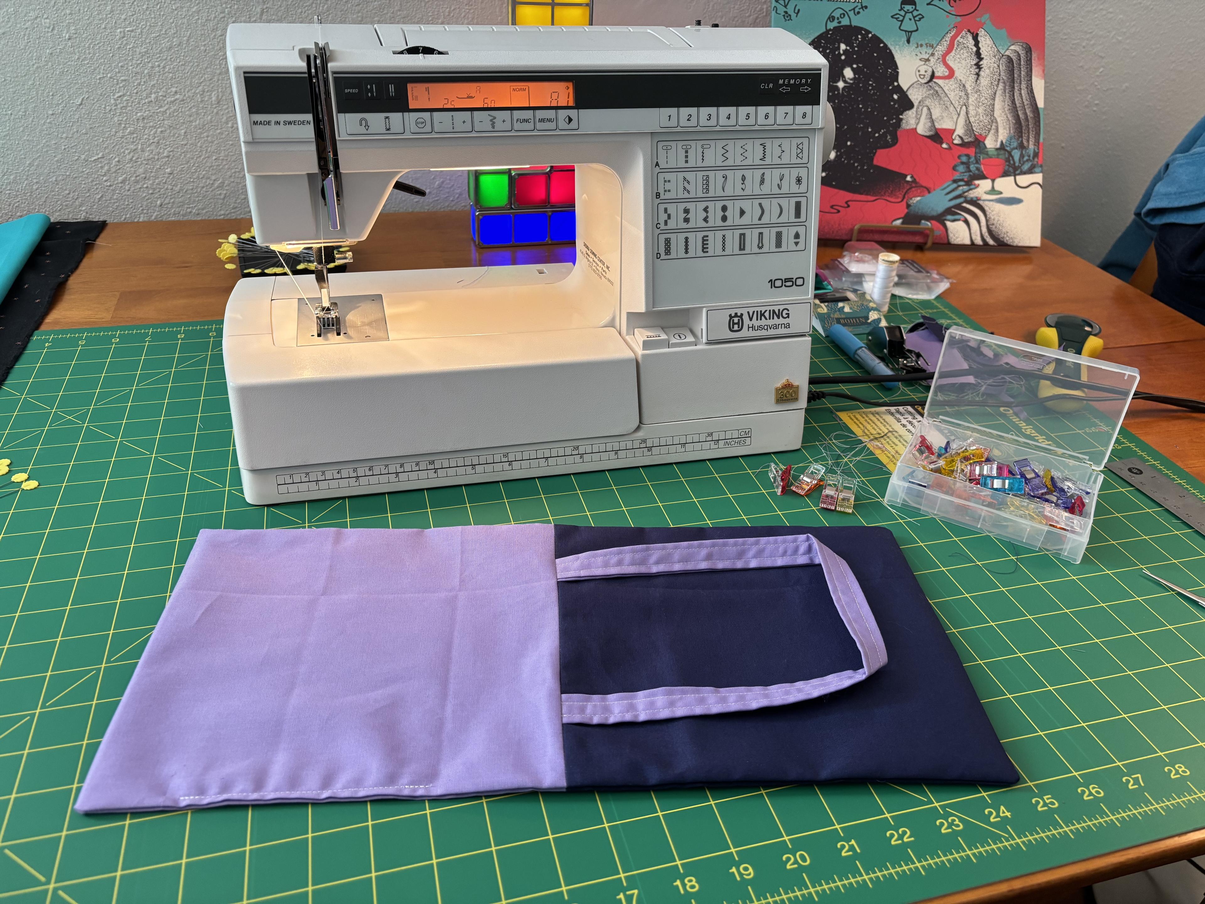 The in-progress tote bag sits on my project table on top of my cutting mat. The lining and the outside are sewn together, and the handles are attached.